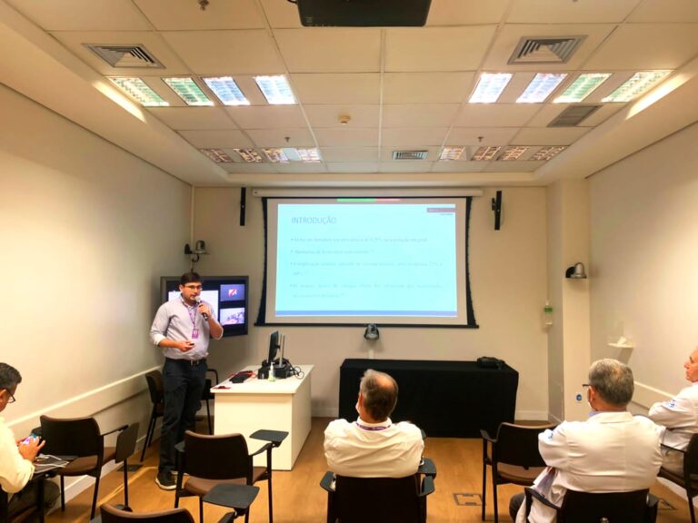 Dr. Thiago Teixeira apresentando palestra sobre rim em ferradura e abordagem cirúrgica no Hospital Sírio-Libanês, destacando técnicas minimamente invasivas e cirurgia robótica.