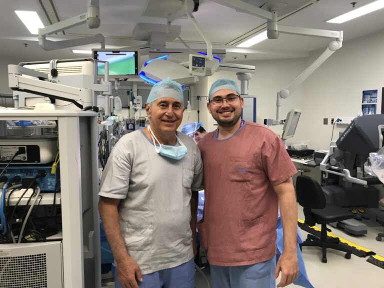 2020 - Dr. Thiago Teixeira ao lado do Dr. Anuar Mitre em centro cirúrgico com a plataforma robótica Da Vinci Si utilizada em cirurgia robótica urológica.